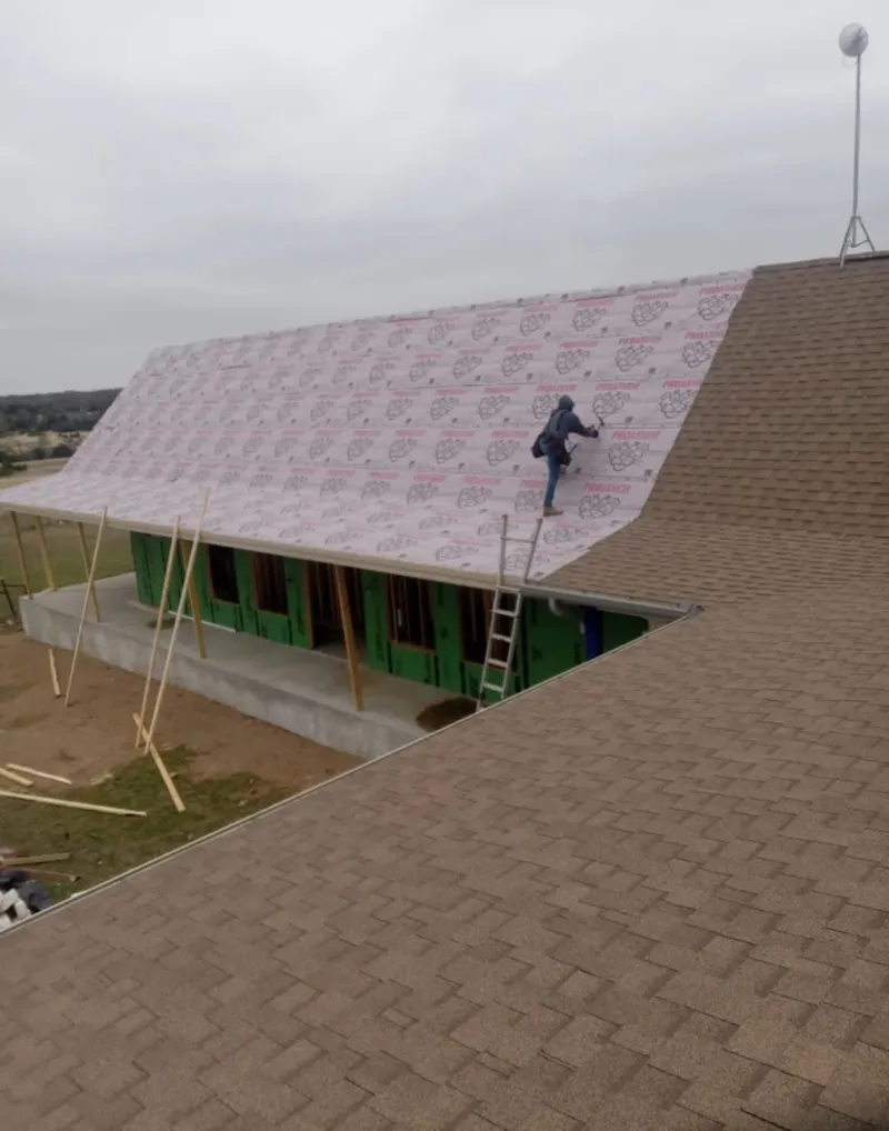Worker preparing underlayment for a metal roof installation in Forestdale